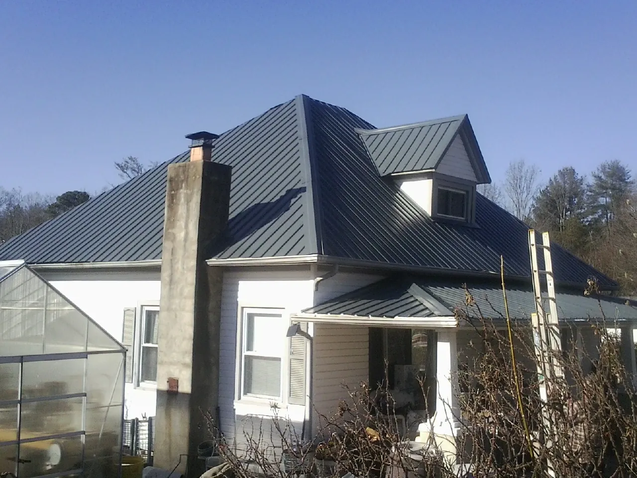 Dark blue standing seam metal roof on a white farmhouse with dormer — Slate & Tile Roof Repair by Roofing Brothers in Tamassee