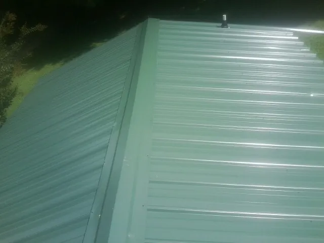 New green metal panels meeting at the ridge of a roof — Flat Roof Repair work by our crew in Tamassee