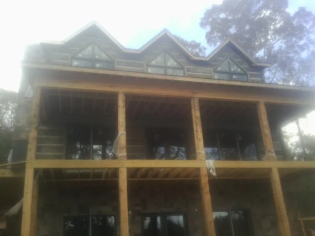 Dormers and porch framing on a large log home under construction — Roof Coating work by our crew in Tamassee
