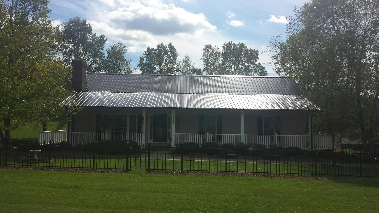 Gray metal roof on a brick ranch with a full width front porch — Gutter Guard Installation work by our crew in Tamassee