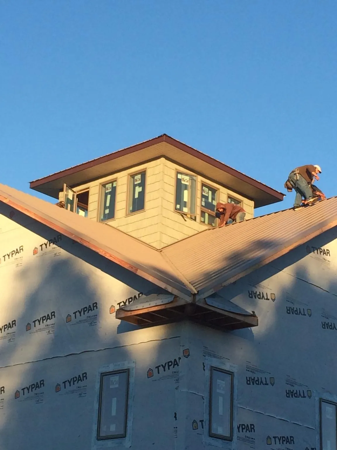 Roofers working around a rooftop cupola on a new metal roof at sunset — Roof Waterproofing in Tamassee by Roofing Brothers